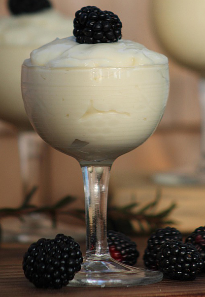 Vanilla pudding in wine glass with raspberry on top