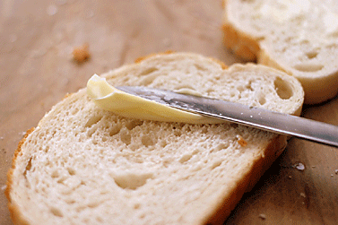 bread being spread with butter with butter knife