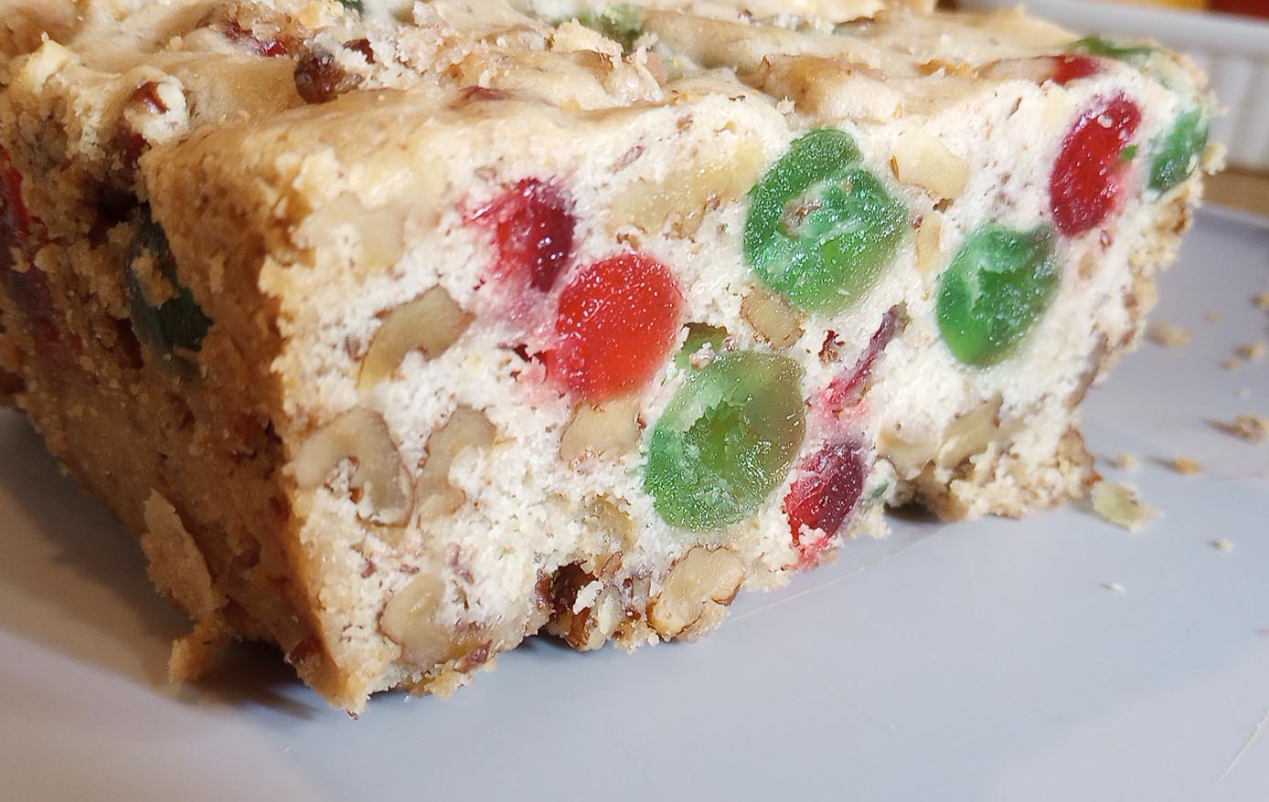 cake with red and green candied cherries and nuts sliced on plate