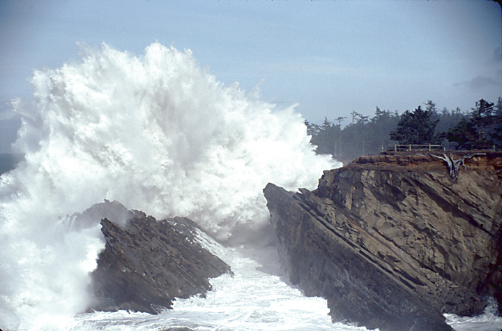 huge wave crashing over tall shore