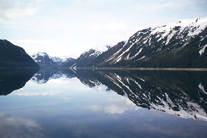 calm ocean with snow covered mountains reflection in alaska