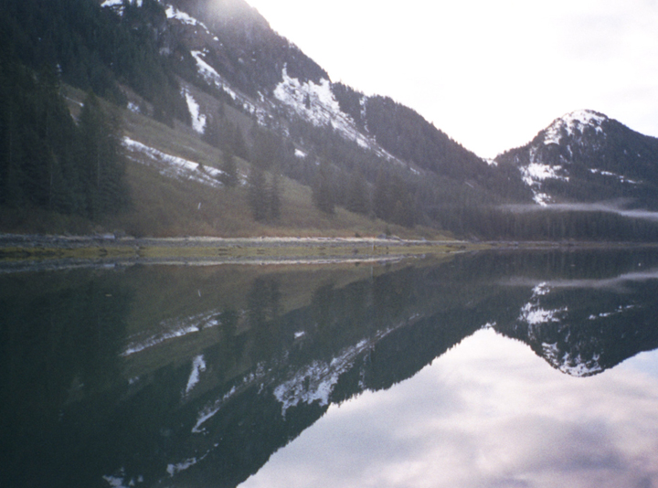 snowy hills and green forest reflection in alaska