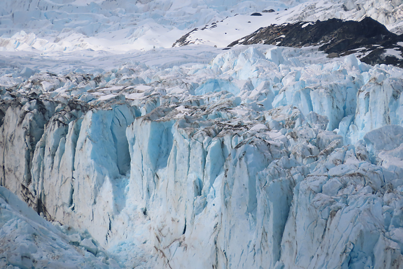 top of glacier, blue white crevasses, sprinkle of black on top in glacier bay Alaska