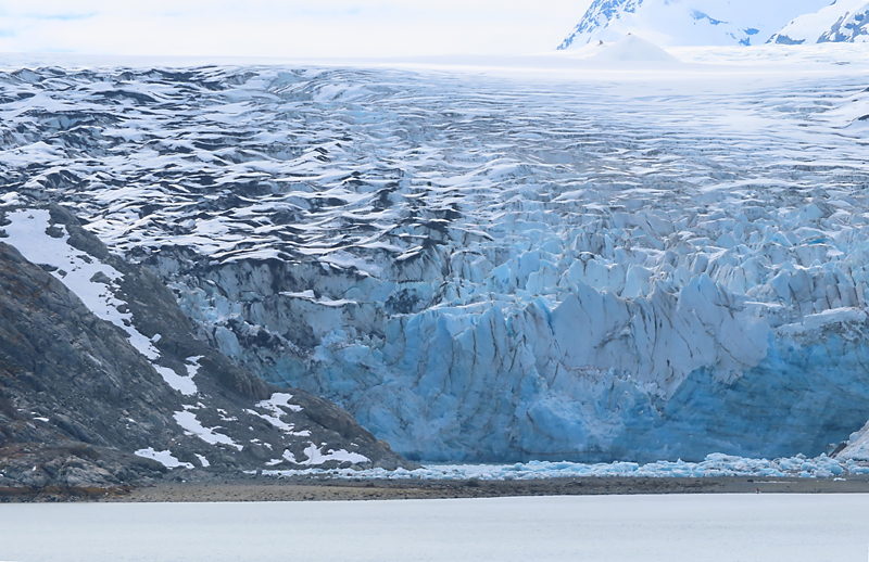blue Lamplugh Glacier, glacier bay Alaska with very small boat and person in front