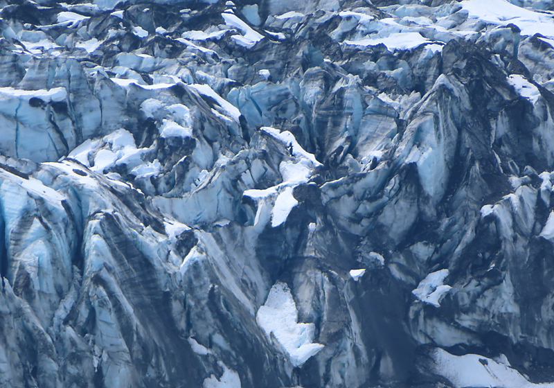Close up of glacier face of blue white and black marble like and snow patches in glacier bay Alaska