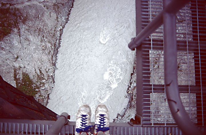 Feet on edge of bridge ready to bungee jump above river