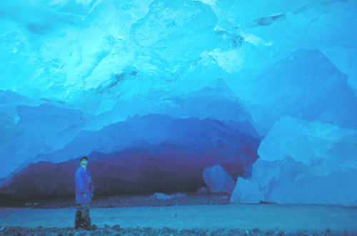 person inside blue icecave in alaska
